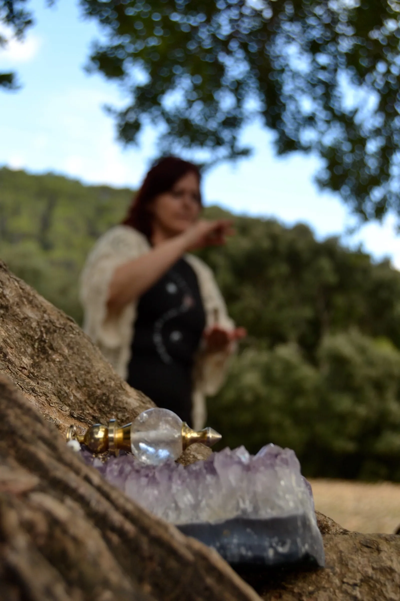 Carmen, en el bosque, trabaja con un péndulo junto a una amatista